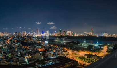 Awesome Ho Chi Minh City skyline. Night view of skyscrapers and other high-rise buildings at downtown of Ho Chi Minh City, Vietnam. Colorful city lights reflected in water of the Saigon River.