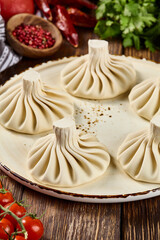 Khinkali on a Plate with Spices, Herbs, and Vegetables on a Wooden Background