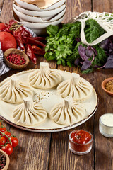 Khinkali Dumplings on a Plate with Spices, Herbs, and Vegetables on Wooden Background