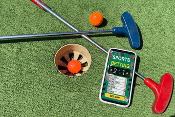golf equipment on the green lawn. mini golf sports betting on a smartphone