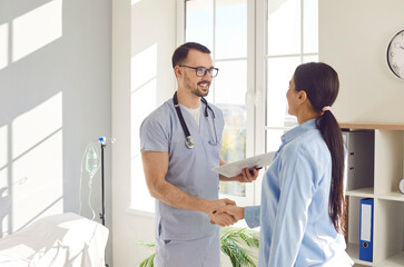 Obraz premium Male doctor welcomes a female patient during visit to the hospital. The nurse extends a handshake, symbolizing the beginning of a compassionate and collaborative healthcare experience.