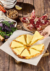Freshly Baked Cheesy Pizza with Various Organic Salad Ingredients and Garnished Pomegranate on Rustic Table