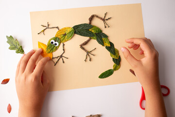 Creative lizard representation using natural materials on beige paper