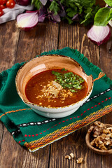 Traditional Kharcho Soup with Veal Garnished with Herbs in Rustic Wooden Setting