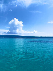 a blue ocean with a white cloud in the sky