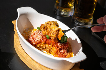 Lasagna portion, oven baked lasagne, pasta layers with cheese, minced meat, tomato in sunny summer day
