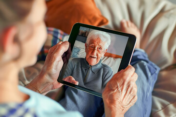 Elderly person joyfully video chats with friend or relative on tablet, embracing modern technology and family connection.