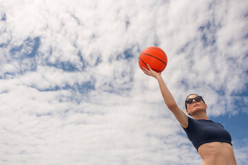Sporty woman about to take a shot with a basketball, low angle view
