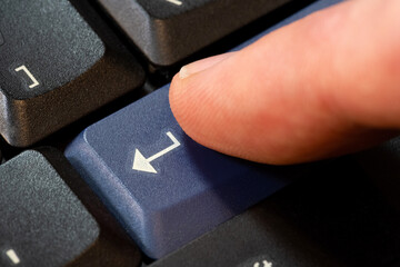 Man's finger pressing a blue enter key on a desktop PC computer keyboard object macro, extreme...