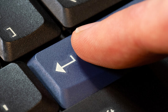 Man's finger pressing a blue enter key on a desktop PC computer keyboard object macro, extreme closeup, one person. Confirming an action, sending a chat message accepting rules simple abstract concept