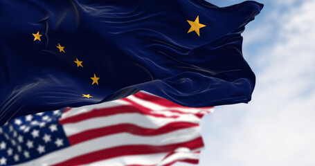 Alaska state flag waving in the wind behind the national flag of the US