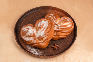 Sweet buns with sugar in the shape of a heart on a ceramic plate, top view