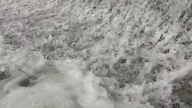close-up of dynamic foamy white water rapids in a rushing river and waterfall with turbulent flow and sparkling reflections under natural sunlight