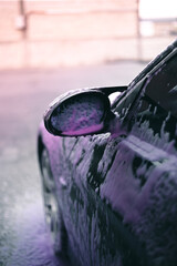 Purple soap foam all over the car waiting to be washed.