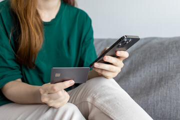 The girl uses a credit card. Internet sales. Girl enters bank details. Girl on the sofa