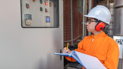 Young engineer working at large factory,Technician in protective uniform and with hardhat  checking temperature in pipes