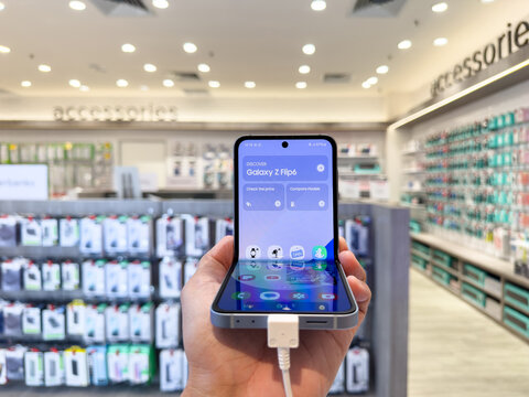PENANG, MALAYSIA - Jul 15, 2024: Hand holding the brand new flagship Samsung Galaxy Z Flip6 mobile phone and showing the unfold display at showroom. Galaxy AI