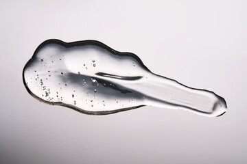 A smear of cosmetic gel close-up on a gray background. Appetizing texture with bubbles.