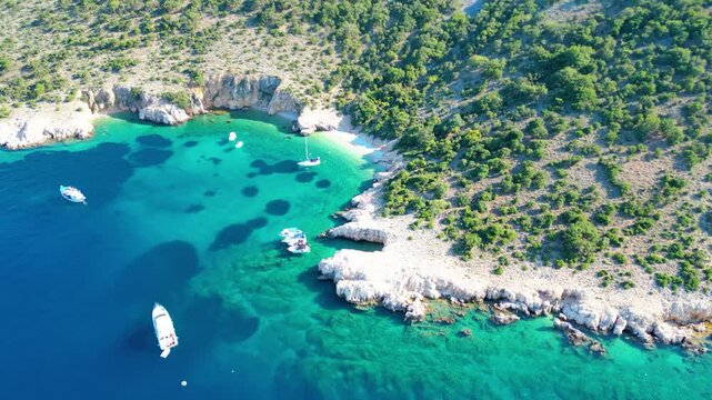 An aerial view of Plavnik and Mali Plavnik islands, captured by drone, with a boat sailing nearby. These picturesque islands are located close to Cres and clear blue water
