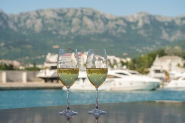Two Champagne Flutes Overlooking a Marina with Yachts and Mountain View