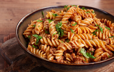 pasta in the navy, pasta with minced meat, plate on a wooden table, homemade, fusilli pasta, without people,