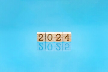 2024の数字ブロックが水面に反射して2025になった青色の背景