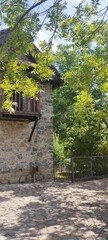 Traditional stone house with wooden balcony and trees