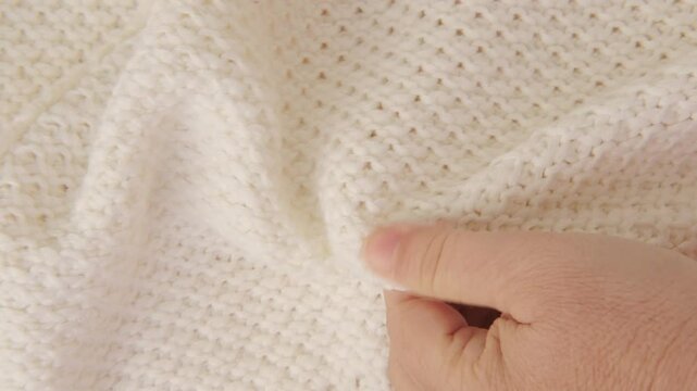 female Hand touching knitted wool cloth or warm fluffy sweater, Handcraft knitting woolen fabric surface, tactile properties, fabric testing