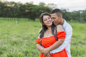 young latin couple, he hugs her from behind while they join cheeks, interracial couple