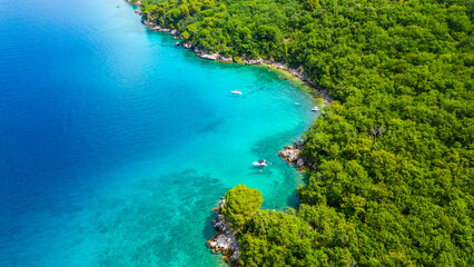 A serene and picturesque beach with turquoise waters, captured by drone on the island of Krk near Glavotok. A boat can be seen drifting on the crystal-clear water, creating a perfect haven for relax