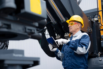 Service diagnostics and repair of hydraulic systems and hoses for industrial truck. Engineer worker uses computer tablet to configure equipment