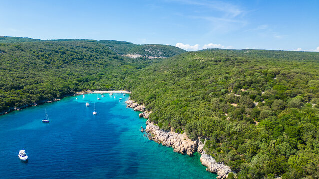 An aerial view of the Blue Lagoon at Plaža Kru&scaron;ćica and Tarej Beach on the island of Cres, showcasing their fantastic turquoise waters and surrounding islands. Boats dot the serene lagoon