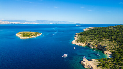 An aerial view of Plavnik and Mali Plavnik islands, captured by drone, with a boat sailing nearby. These picturesque islands are located close to Cres and clear blue water © Viktor