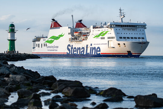 StenaLine ferry Mecklenburg Western Pomerania passing the pier fire. Warnow estuary - entrance to Rostock harbor. Ferry at sunset. Warnem&uuml;nde, Mecklenburg-Western Pomerania, Germany - 06 22 2023
