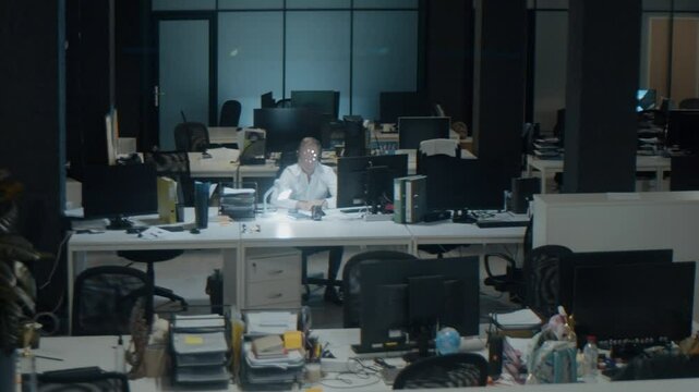 Male employee works in empty office late at night. Man loading. High quality 4k footage
