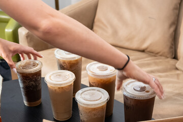 Coffee shop drinks are arranged in order by female hands with individual names on cups