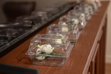 Boutoniere flowers for the groom and groomsmen lined up and protective boxes