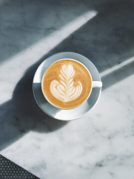latte on marble in sunshine and shadows at coffee shop
