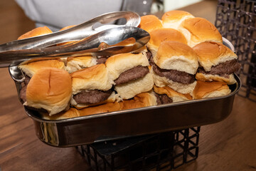 Hamburger sliders were out on serving dishes for party guest still hungry to eat