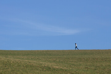 Person walking on open field under clear sky