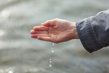 Hand with drops above water surface