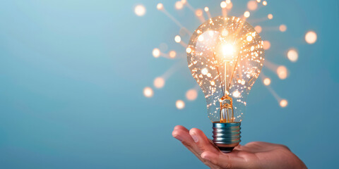 A hand holding a glowing light bulb with sparkles against a blue background, symbolizing innovation and new ideas. Perfect for technology, creative industries, and businesses focused on inspiration