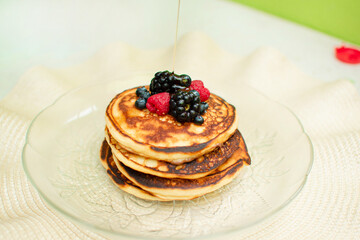 Desayuno de panqueques con frutos rojos en una mesa
