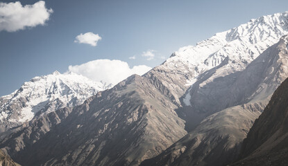 Panorama of mountain range of rocks with snow and glaciers in Pamir in Tajikistan mountains in cloudy weather, minimalistic landscape of high mountains for background
