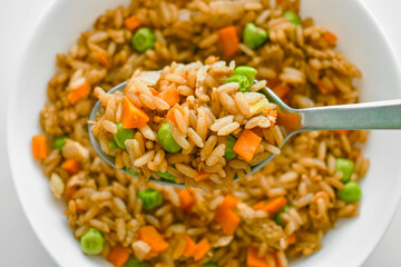Egg fried rice with dark soy sauce, carrot and peas on spoon. Asian food style. 