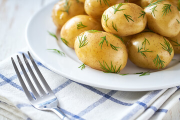 close up,tasty boiled new potatoes with fresh dill in a wooden table.