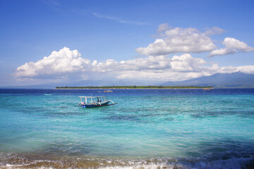 Fototapeta premium Small tourist boat in the serene turquoise waters of a tropical Gili Meno island on a clear sunny day
