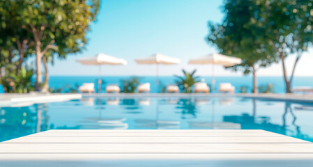 Empty Wood table top on blurred bokeh background of hotel in the tropics. Summer background with blue pool, sun loungers and umbrellas, palm trees,sea.For display or montage products, summer holidays