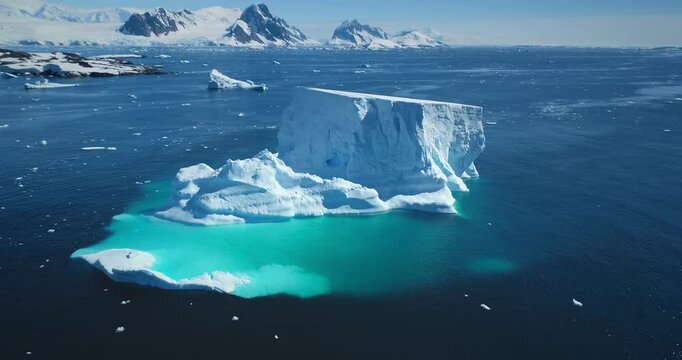 Giant iceberg towering melting blue underwater ice. Natural beauty and power. Polar winter landscape in Antarctica. Ecology, melting ice, climate change, global warming background. Aerial drone shot