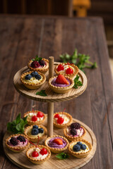 Berry tartlets with butter cream lie on a wooden whatnot outdoors on the table